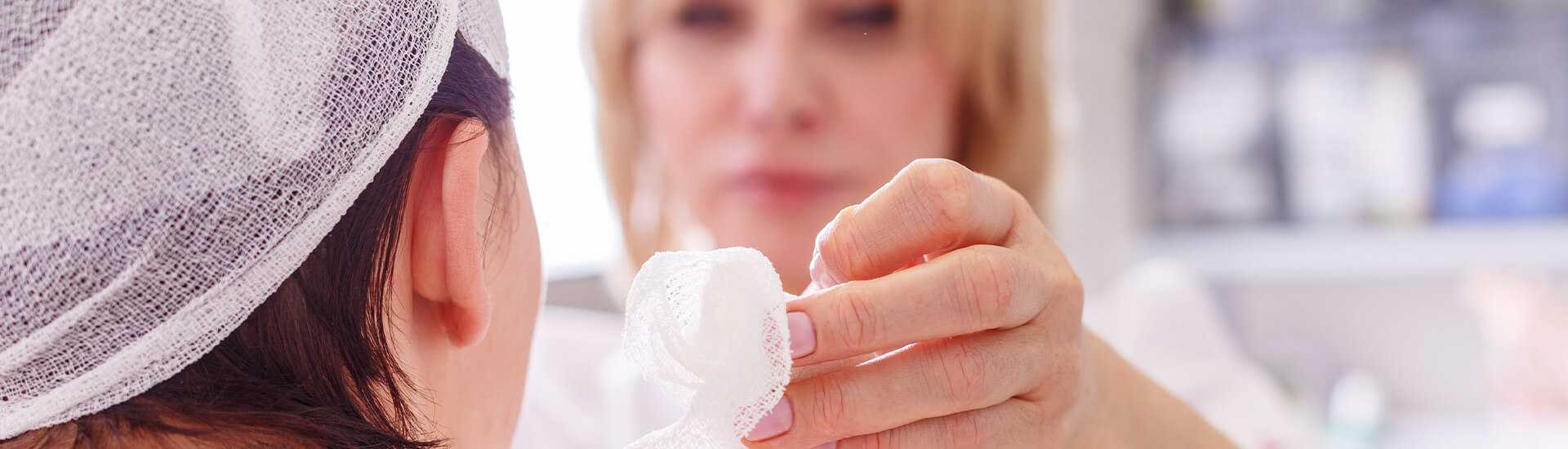 Photo of a doctor removing gauze from a woman's face