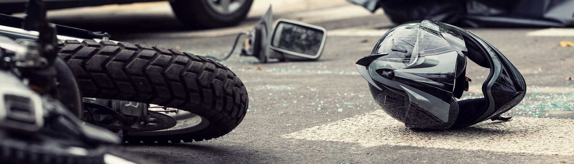 Photo of a motorcycle accident and empty helmet on the pavement