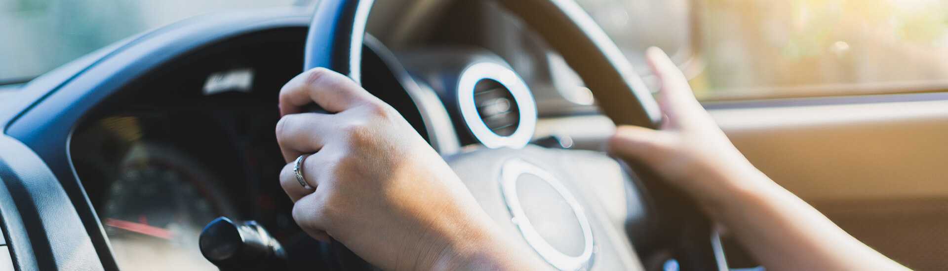 Photo of female hands holding a steering wheel while driving